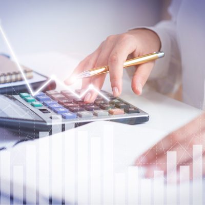 Accountant calculating profit with financial analysis graphs. Notebook, glasses and calculator lying on desk. Accountancy concept. Cropped view.